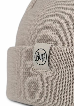 Helle beige gestrickte Mütze mit umgeschlagenem Saum, ausgestattet mit einem weißen Stoffetikett mit schwarzem "Buff"-Logo. Strukturmaterial mit geripptem Muster.