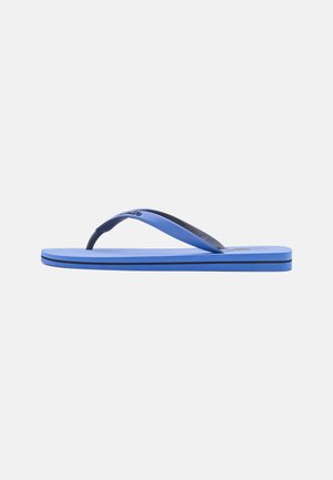 Blå flip-flop sandal med en sort stribe på sålen og matchende blå stropper, vist fra siden på en hvid baggrund.
