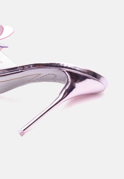 Λαμπερό μεταλλικό ροζ ψηλοτάκουνο στιλέτο με διαφανή λουράκι και διακοσμητική ροζ ανθοδέσμη κοντά στον αστράγαλο σε λευκό φόντο.