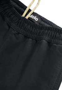 Sorte elastiske shorts med snøring, med en jevn tekstur og minimal søm. Merket "Molo" synlig på toppen.