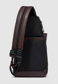 Borsa a tracolla in pelle marrone e tessuto nero con superficie strutturata, più scomparti con zip e spallacci regolabili.