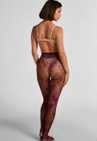 Calze autoreggenti color bordeaux con motivi floreali, texture trasparente e vita alta. Vista posteriore che mostra dettagli intricati e una silhouette aderente.