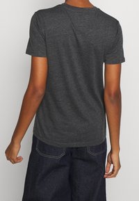 Kulkulsort kortærmet t-shirt med rund hals, blød tekstur og afslappet pasform, båret med mørke denim bukser.