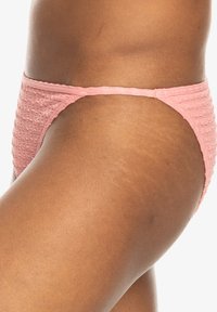 Rosa bikiniunderdel med en texturerad, rynkad tygdesign. Midjebandet är slätt, och skärningen är låg med minimal täckning.