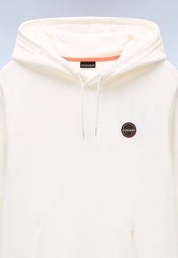 Cream-colored hooded sweatshirt with drawstrings and a small round black and orange logo on the chest.
