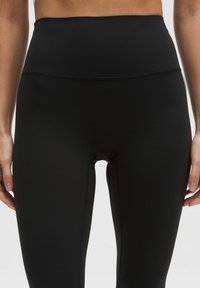 Leggings negros de tiro alto con una tela suave y elástica, con costuras planas y un diseño ceñido para mayor comodidad y libertad de movimiento.