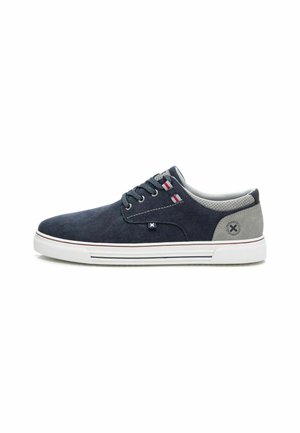 Zapato de ante azul marino con acentos grises, suela de goma blanca y detalles en rojo y blanco en la lengüeta. Diseño plano y textura suave.