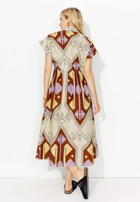 Robe midi en tissu à motifs avec des designs géométriques dans des tons marron, jaune, lavande et crème. Manches courtes et col classique.