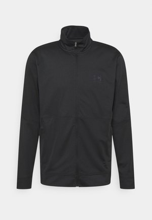 Schwarze Jacke mit Reißverschluss, Stehkragen, langen Ärmeln und dezentem Logo auf der linken Brust, vor hellem Hintergrund präsentiert.