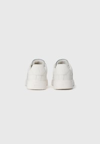 Et par hvide ARKK sneakers vist fra bagsiden på en ensfarvet lys baggrund.