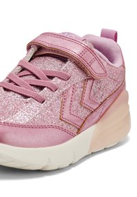 Baskets de sport roses avec un dessus scintillant, des lacets en tissu et une sangle velcro. Comprend une semelle intermédiaire texturée et une semelle extérieure en caoutchouc pour l'adhérence.