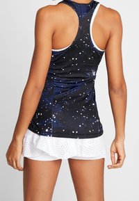 Mustavalkoinen ja sininen racerback-hihaton toppi, jossa galaksipainatus; siinä on valkoisia yksityiskohtia ja istuva malli, yhdistettynä valkoiseen kerrokselliseen shortshameeseen.