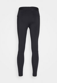 Leggings de sport noirs taille haute avec une silhouette ajustée et des détails de coutures au-dessus des mollets, vus de dos.