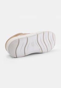 Beige színű sneaker, texturált felsőrésszel és vastag, fehér gumitalppal, melyen bordák találhatóak a tapadásért. A talp oldalán dombornyomott logó.