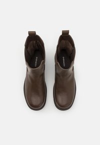 Stivaletti in pelle marrone con finitura liscia, punta tondeggiante e pannelli laterali elastici. Dotati di un tassello per facilitare la calzata.