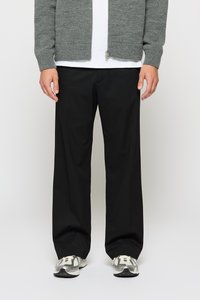 Grauer gestrickter Cardigan, schwarze lockere Hose und graue Sportschuhe. Der Cardigan hat einen Reißverschluss; die Schuhe haben ein strukturiertes Design.