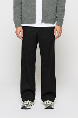 Gray knitted cardigan, black loose-fitting trousers, and gray athletic shoes. Cardigan has a zip closure; shoes feature a textured design.