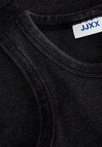 Svart ribbestrikket tanktopp med teksturert finish. Har rund halslinning og et merke med "JJXX"-logo.