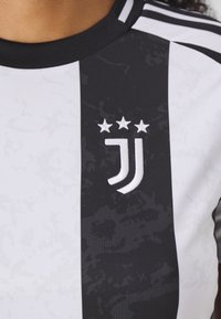 Das Trikot von Juventus hat schwarz-weiße Streifen, einen strukturierten Stoff mit einem dezenten Muster und ein weißes gesticktes Wappen mit drei Sternen.