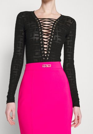 Haut noir à manches longues avec un col lacé profond, associé à une jupe taille haute rose vif avec une petite boucle dorée.