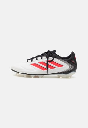 Bota de fútbol Adidas Copa en blanco, negro y rojo, con cordones negros y tacos moldeados sobre un fondo blanco.