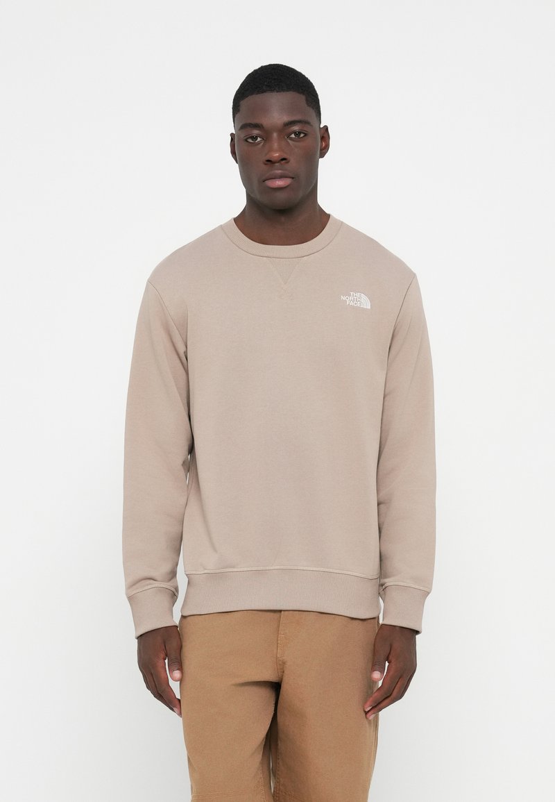 Beiger Sweatshirt mit gerippten Bündchen und Saum. Enthält ein kleines weißes Logo auf der linken Brustseite. Hergestellt aus weichem Stoff mit einer lockeren Passform.