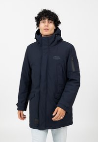 Marineblauer Parka mit Kapuze, Vorderreißverschluss, zwei vorderen Taschen und einer Ärmeltasche; mit einem Logo auf der Brust und kontrastierenden Details.