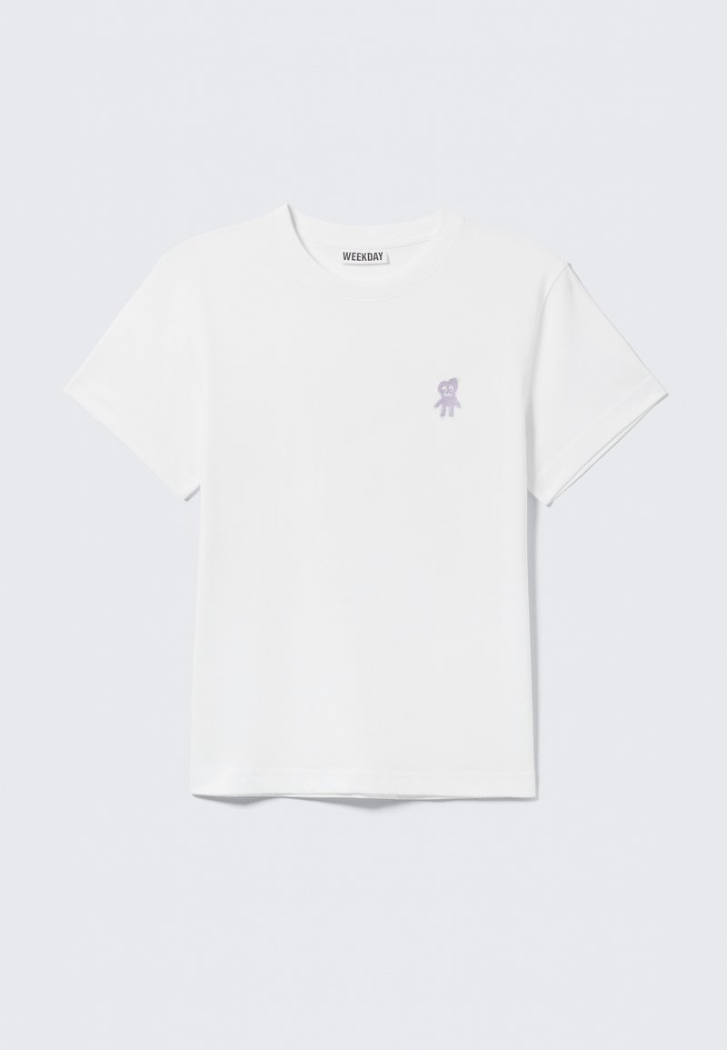 T-shirt en coton blanc avec un petit motif d'ours violet sur le côté gauche de la poitrine ; col rond classique et manches courtes.