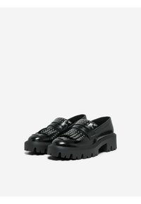 Mocassins noirs en vernis avec une semelle plateforme épaisse, dotés d'accents cloutés et de superpositions à franges sur le devant. Texture lisse.