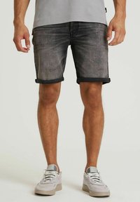 Shorts in denim neri con risvolti, caratterizzati da una texture sbiadita e un minimo di usura. Abbinati a sneakers grigie chiare.