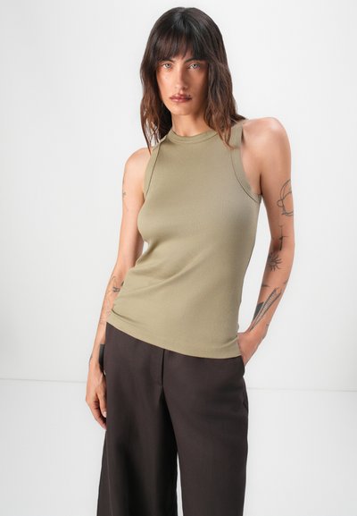 Olive green ribbed tank top with a high neckline and sleeveless design, paired with dark brown wide-leg trousers. Smooth texture, fitted style.