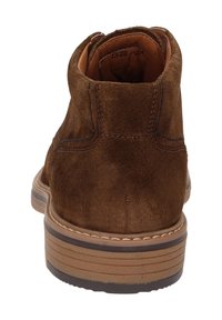 Stivale alla caviglia in camoscio marrone con punta arrotondata, dettagli cuciti e suola in gomma texturizzata. Presenta un tacco basso e colletto imbottito.