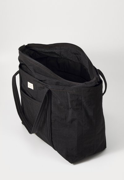 Black fabric tote bag with a zip closure, two handles, and an interior pocket. Textured surface with contrasting stitching details.