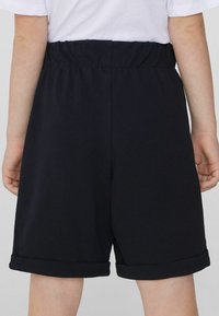 Shorts noirs à taille élastique en tissu texturé, avec des ourlets à revers. Conçus pour le confort et la liberté de mouvement.