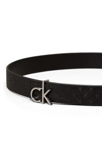 Sort læderbælte med et subtilt prægning mønster og en sølvfarvet metalspænde, der har bogstaverne "ck." Justerbart med flere huller.