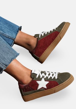 Sneaker en suède vert et en velours côtelé bordeaux avec détail en étoile blanche, semelle en caoutchouc et lacets blancs. Cheville exposée avec un denim effiloché.