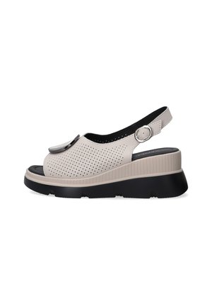 Beige slingback sandaler med perforeret overdel, rund tå og en kraftig sort sål. Udstyret med en metallisk detalje og justerbar rem.