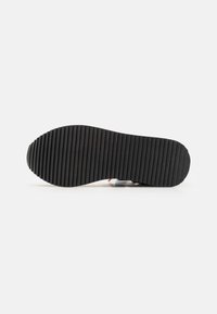 Black rubber shoe sole with a textured, ribbed pattern for grip and durability; rounded toe and slight curve at the heel.