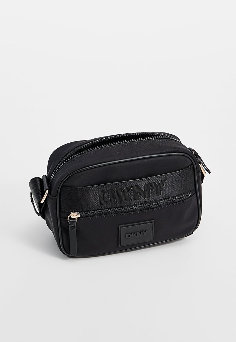 Bolso bandolera negro hecho de nailon con una textura suave, que cuenta con un cierre de cremallera, logotipo DKNY en relieve y una correa desmontable.