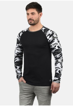 Schwarz mit langen Ärmeln, camouflage-gemusterte graue und weiße Ärmel, runder Halsausschnitt und figurbetontes Design. Aus weichem Stoff gefertigt.