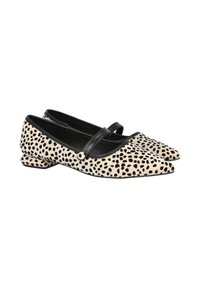 Zapatos planos de punta en crema con lunares negros, con una correa de cuero negra y tacón bajo. Textura suave y diseño elegante.