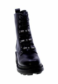 Bottine en cuir noir avec un bout rond, présentant des œillets métalliques et des lacets épais, une semelle en caoutchouc texturée et un talon épais.