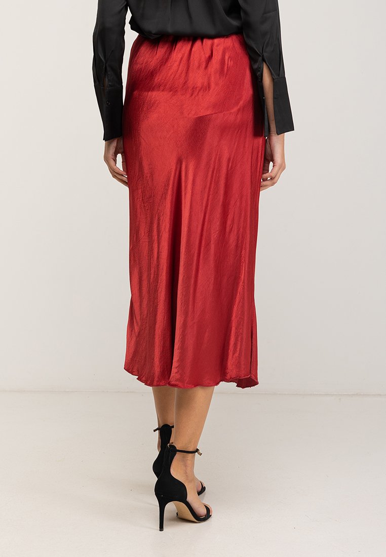 Rode satijnen midi-jurk met een uitlopende snit en een subtiele glans. Beschikt over een elastische tailleband en zijsplitten voor meer bewegingsvrijheid.
