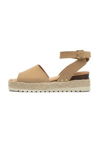 Tan suede sandal with open toe, adjustable ankle strap, woven jute platform, and textured rubber sole; features gold-toned hardware accents.