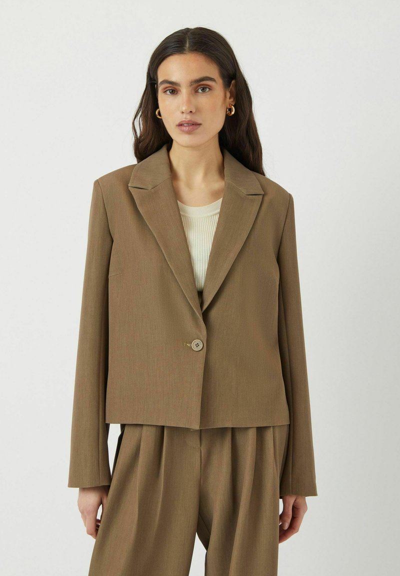 Hnědý přizpůsobený blazer s klopami, zapínáním na jeden knoflík a dlouhými rukávy. Texturovaná látka a zkrácený střih.