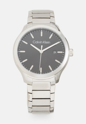 Montre en acier inoxydable argenté avec un cadran noir, des index argentés et un affichage de la date. Boîtier rond et bracelet à maillons avec une finition polie.