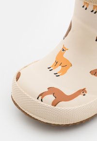 Botte en caoutchouc avec une base crème, ornée de motifs de lamas colorés. Semelle texturée pour une bonne adhérence et bord renforcé pour la durabilité.