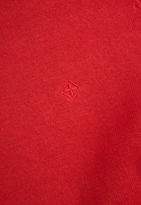 Czerwony dziergany sweter o fakturowanym wykończeniu. Z małym haftowanym logo w dolnym rogu. Miękka, elastyczna tkanina.