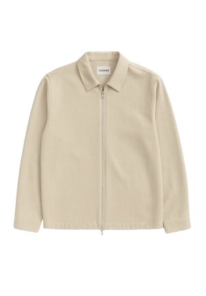 Beige zip-up jakke med krage, lange ermer, glatt tekstur og minimal detaljer; merket sier "CISZERE."