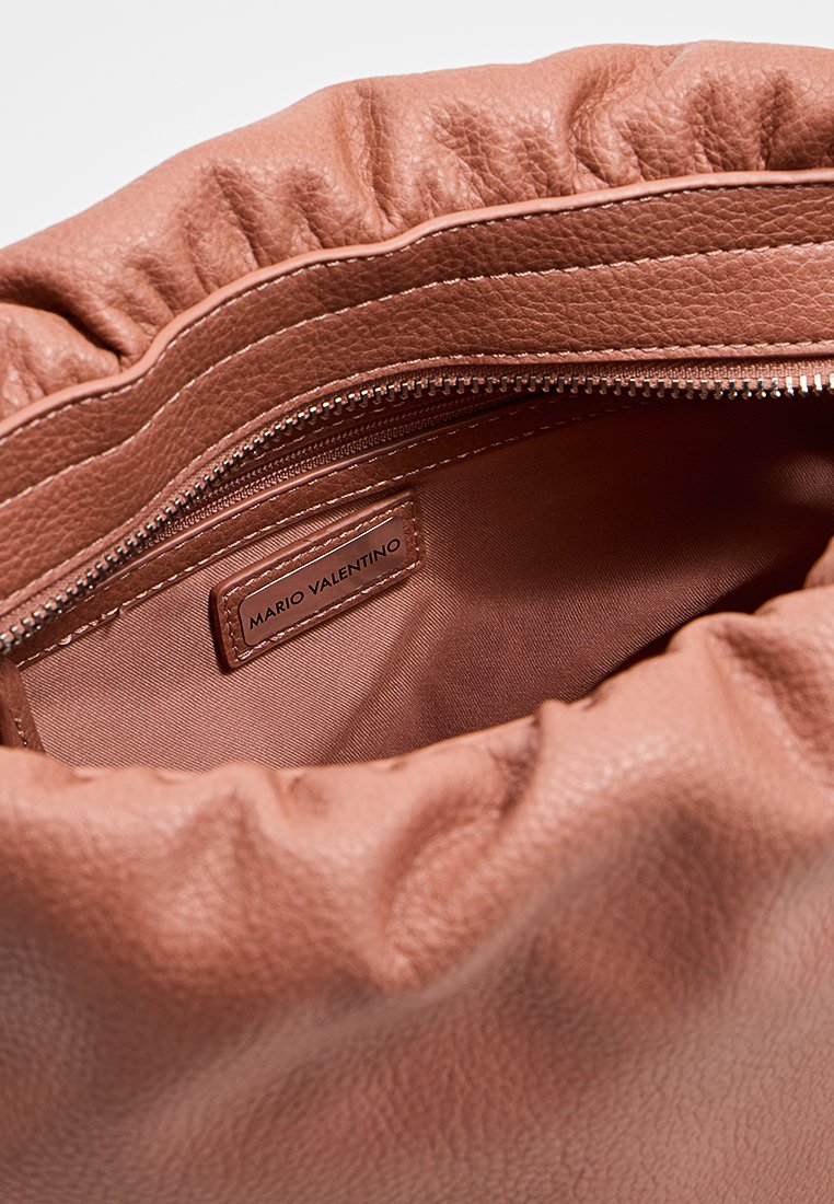 Interior de un bolso de cuero marrón texturizado con parte superior fruncida, que cuenta con un bolsillo con cremallera y una etiqueta que dice "MARIO VALENTINO". Forro de satén suave.